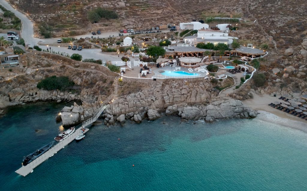 vue du ciel du restaurant posé sur une falaise avec sa piscine avec à ses pieds l'une des plus belles plages de Mykonos