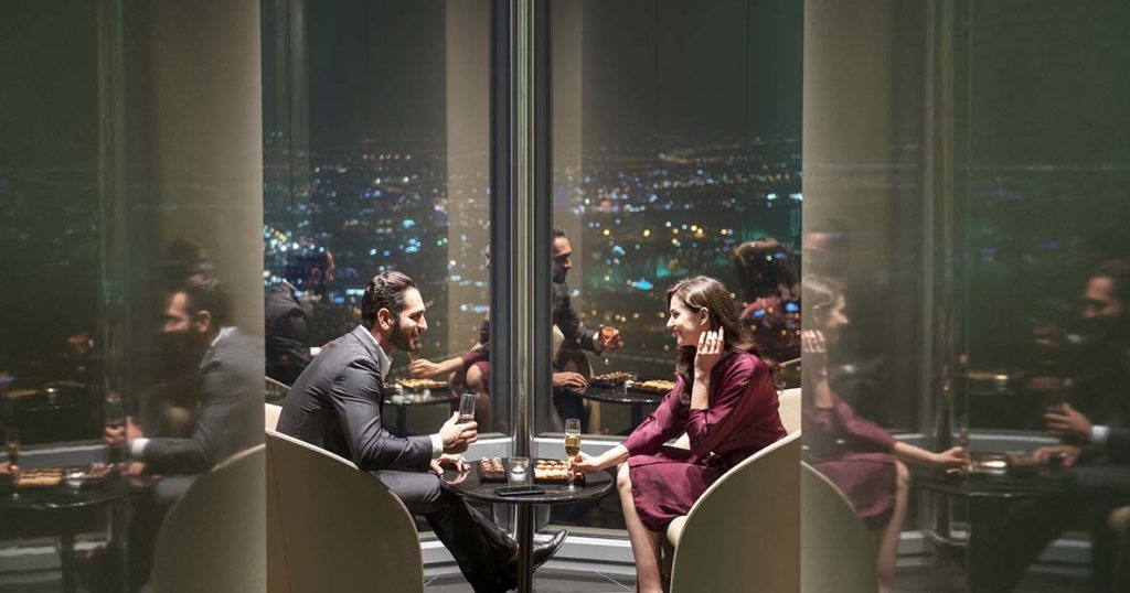 Un couple qui trinque et mange dans un salon au dernier étage de la tour Burj Khalifa à Dubai .