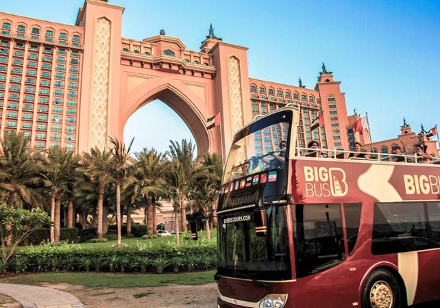 Bus à étage qui roule sur une route avec l'hôtel Atlantis en arrière plan, une des activités à faire à Dubai