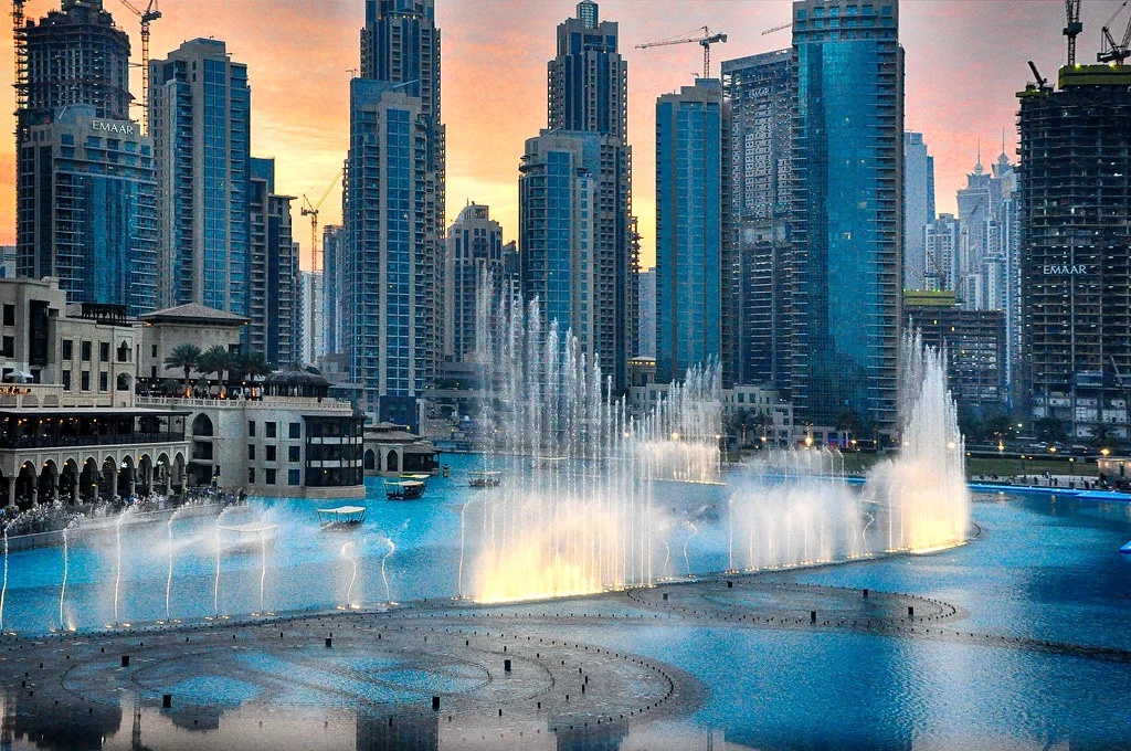 Fontaine dansante sur le lac artificiel au pied de la Burj Khalifa à Dubai avec en arrière plan les buildings 